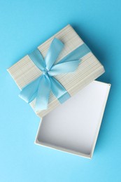 Photo of Gift box with bow on light blue background, top view