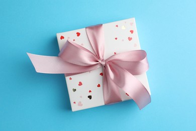 Gift box with bow on light blue background, top view