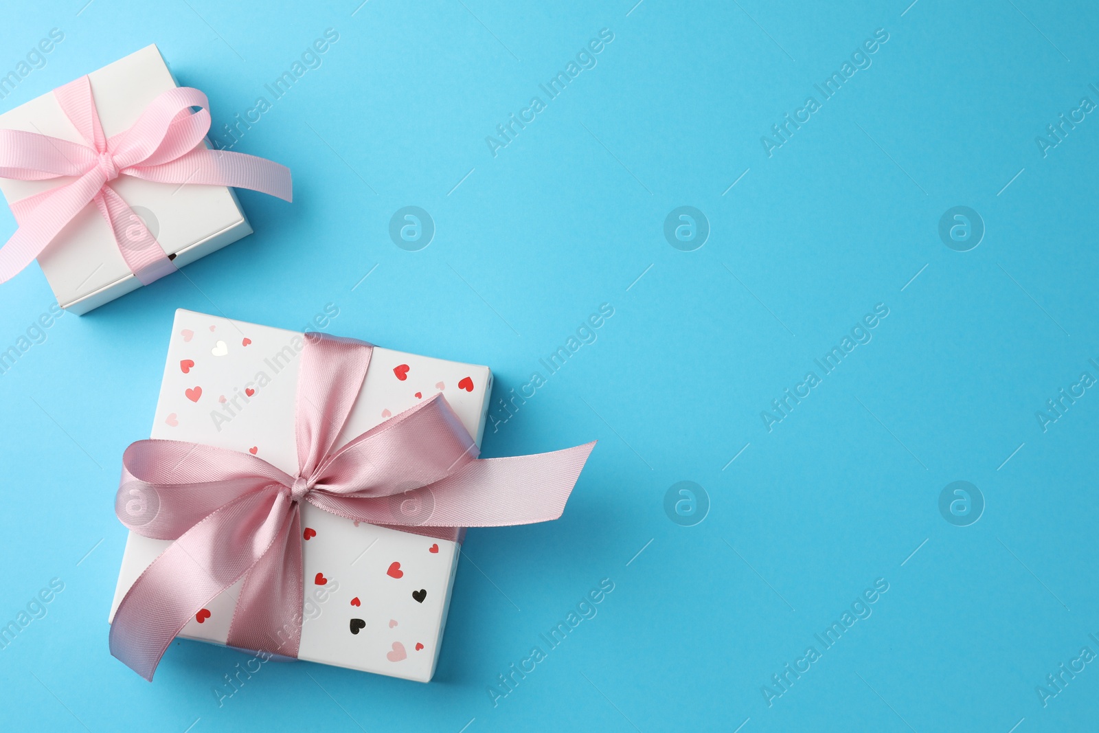 Photo of Gift boxes with bows on light blue background, flat lay. Space for text