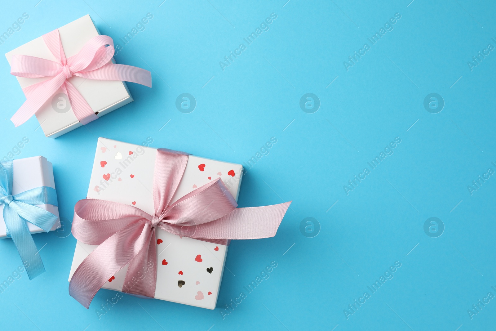 Photo of Gift boxes with bows on light blue background, flat lay. Space for text