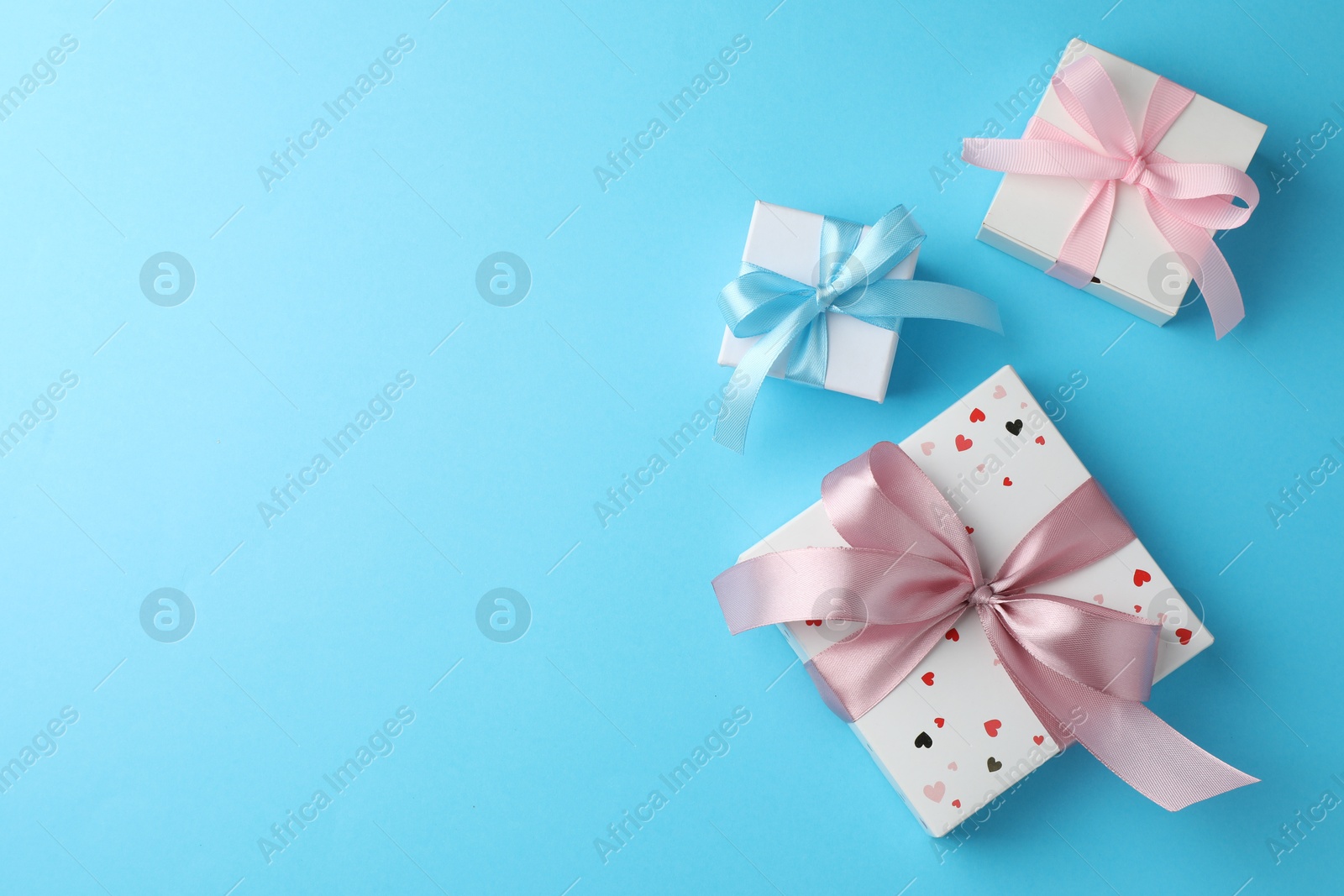 Photo of Gift boxes with bows on light blue background, flat lay. Space for text