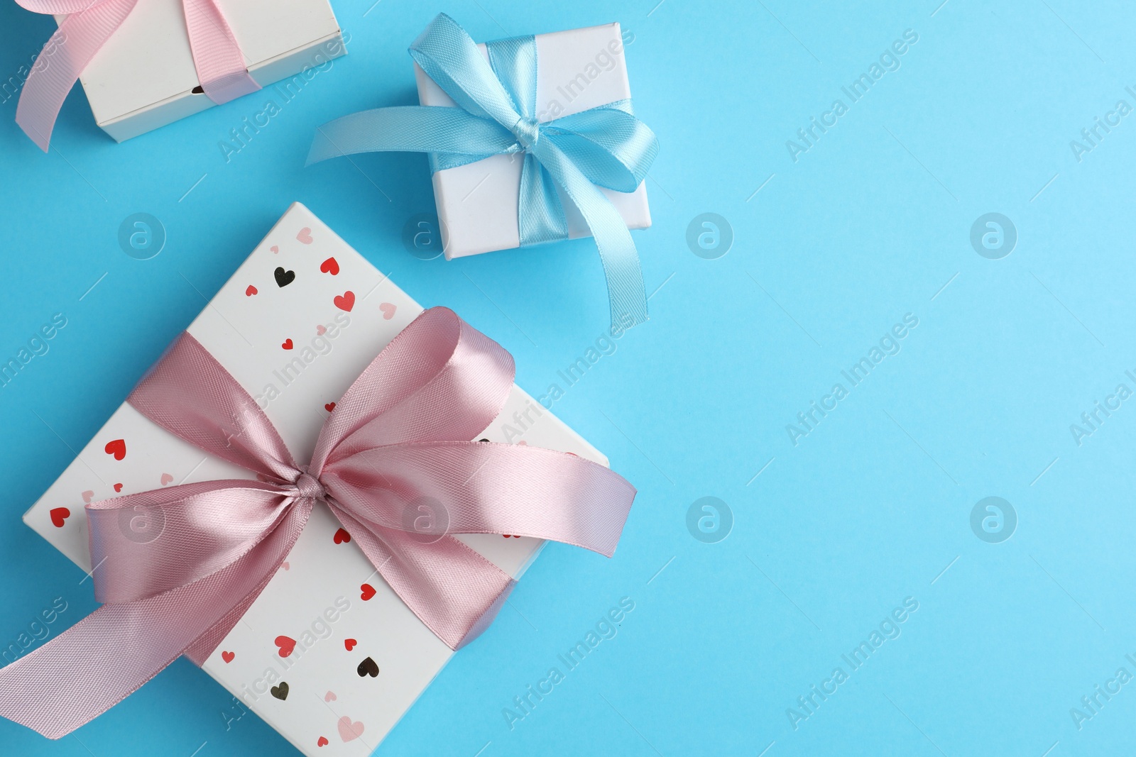 Photo of Gift boxes with bows on light blue background, flat lay. Space for text