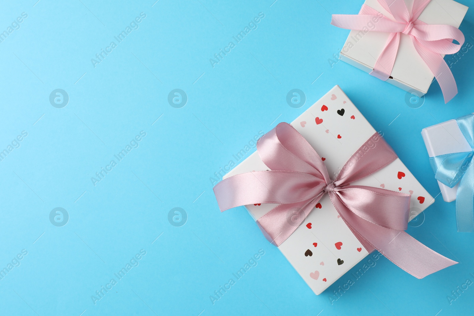 Photo of Gift boxes with bows on light blue background, flat lay. Space for text