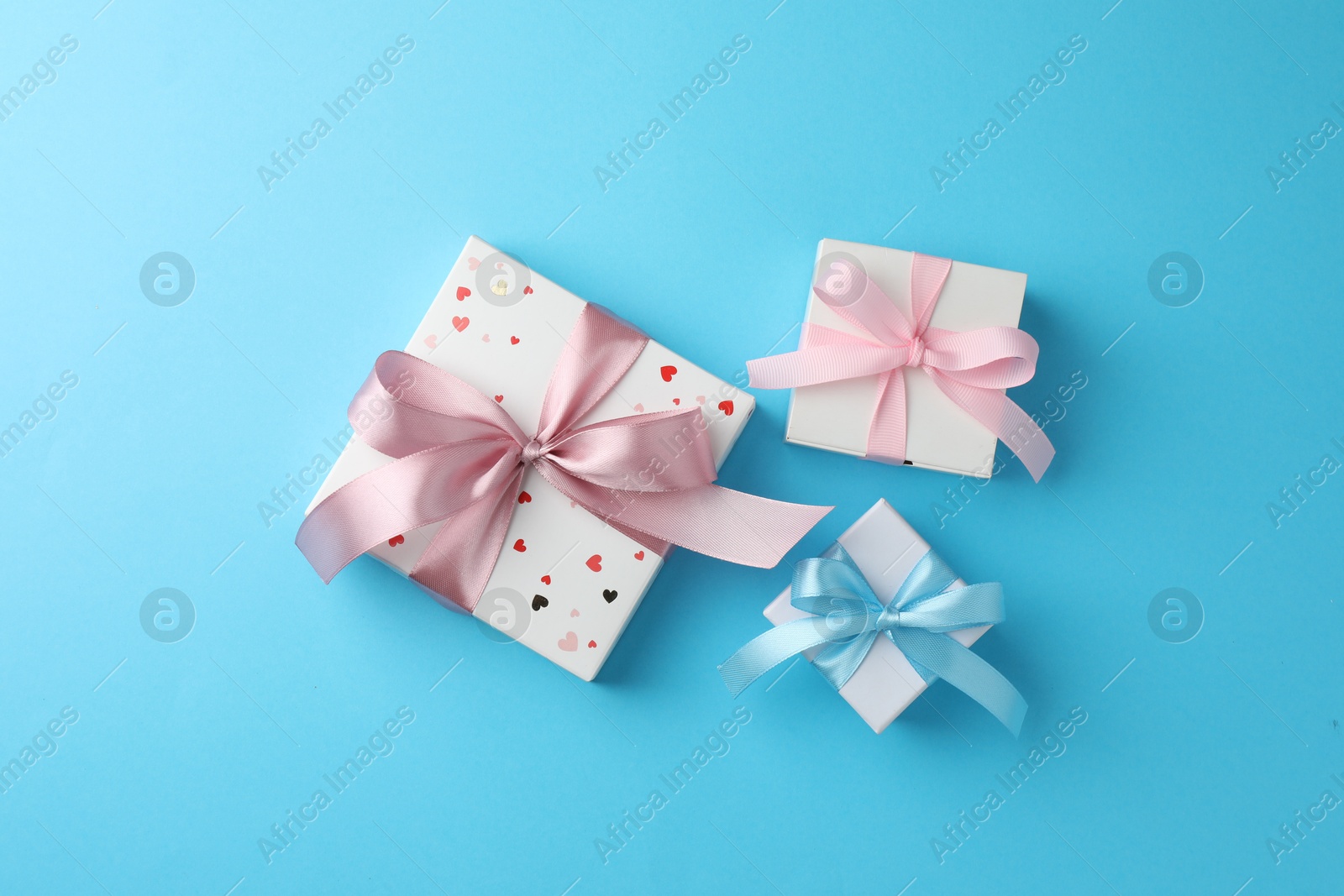 Photo of Gift boxes with bows on light blue background, flat lay