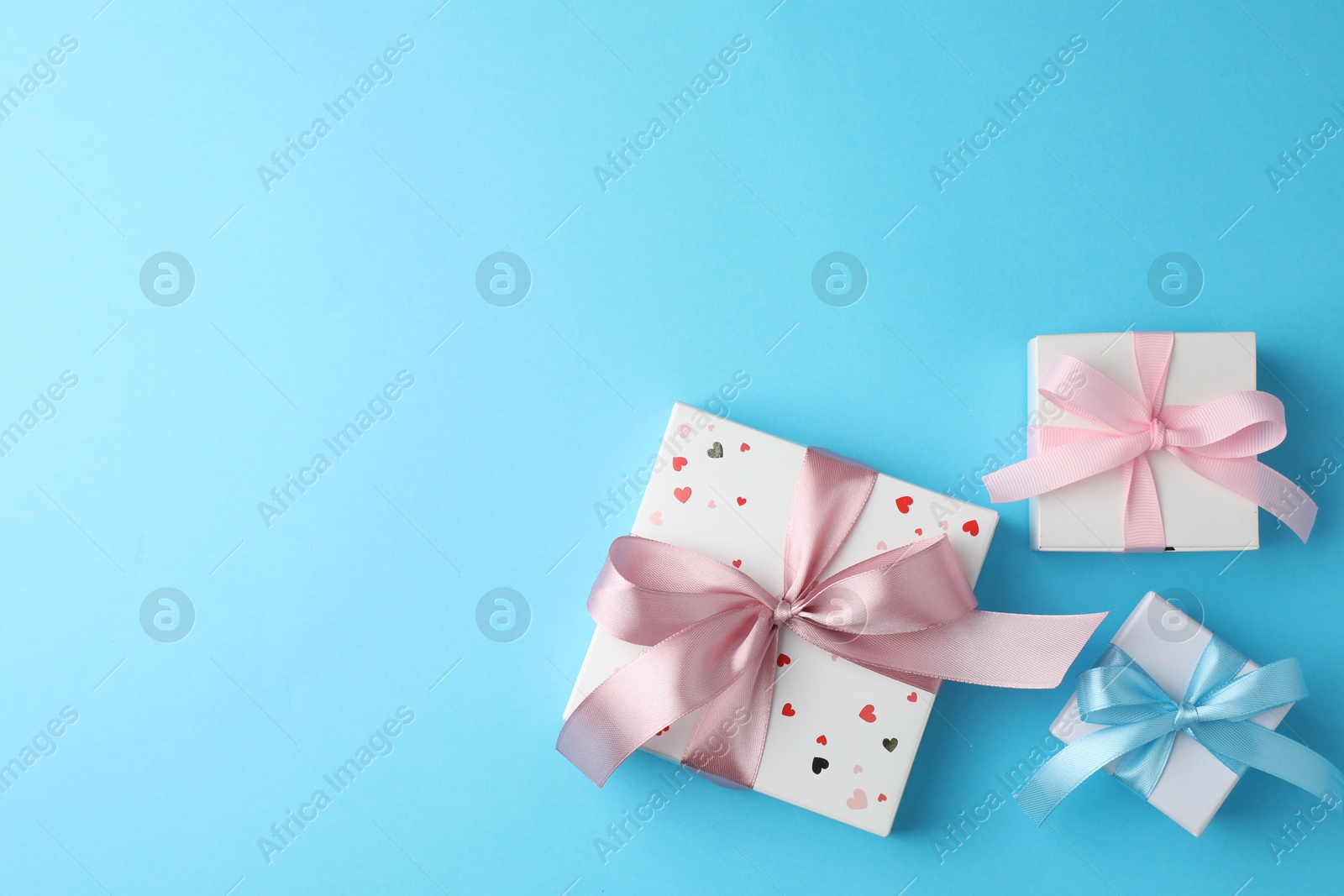 Photo of Gift boxes with bows on light blue background, flat lay. Space for text