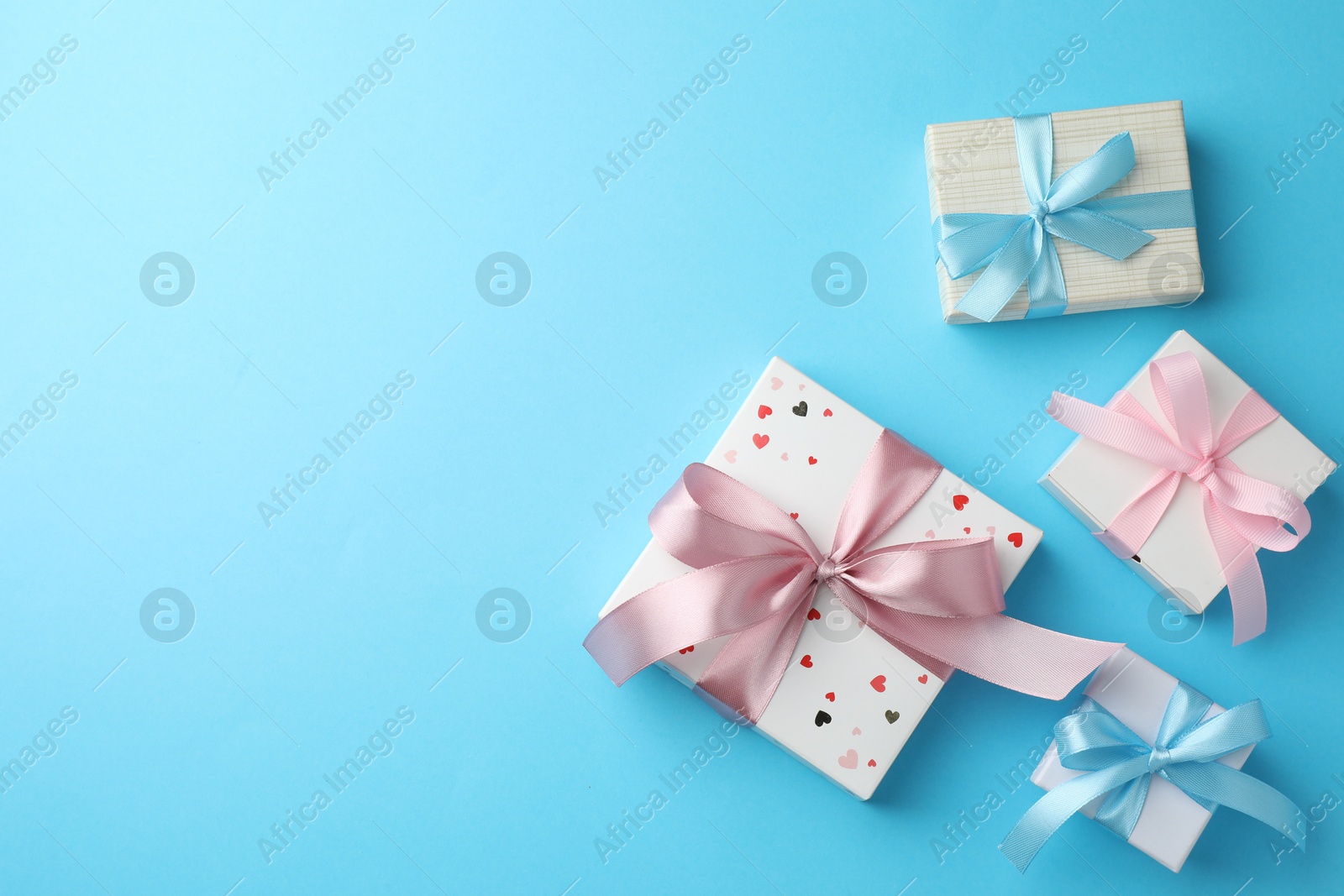 Photo of Gift boxes with bows on light blue background, flat lay. Space for text