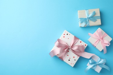 Gift boxes with bows on light blue background, flat lay. Space for text