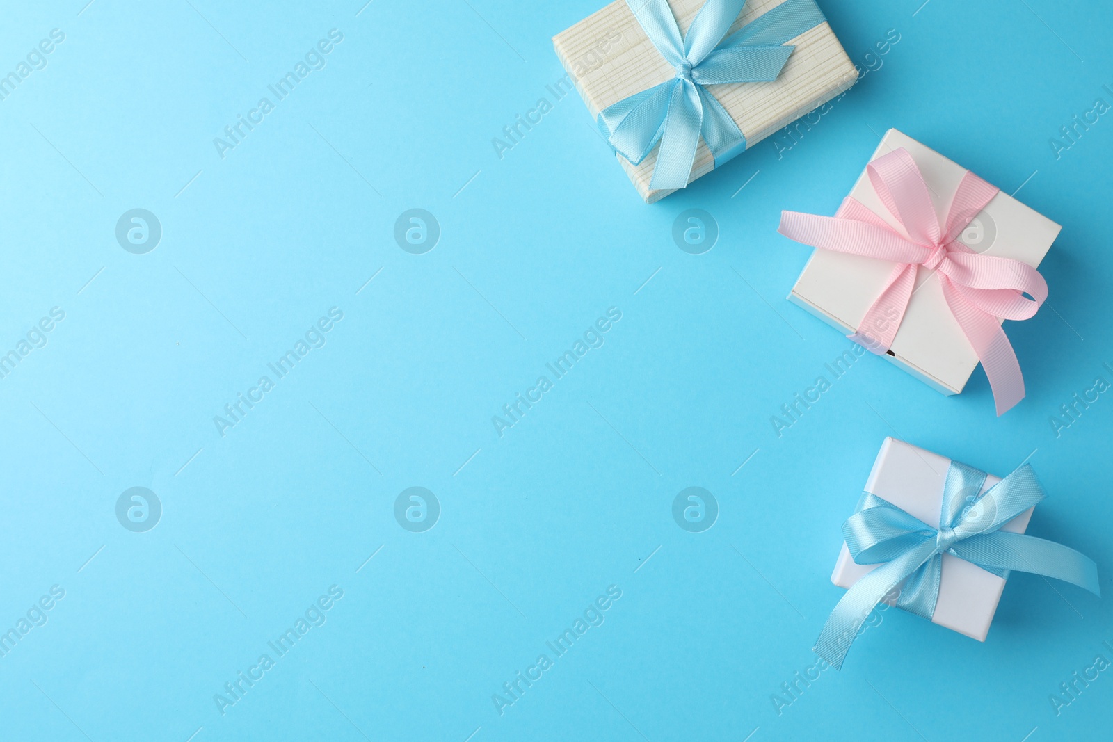 Photo of Gift boxes with bows on light blue background, flat lay. Space for text