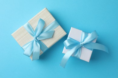 Gift boxes with bows on light blue background, flat lay