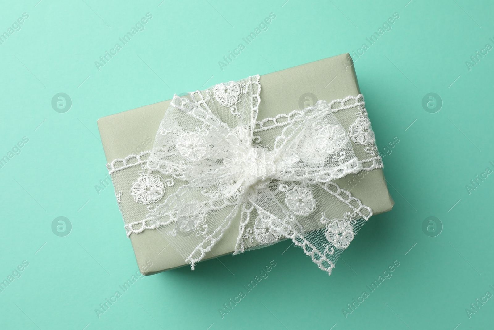 Photo of Gift box with bow on turquoise background, top view