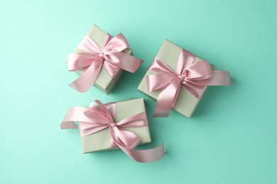 Photo of Gift boxes with bows on turquoise background, flat lay