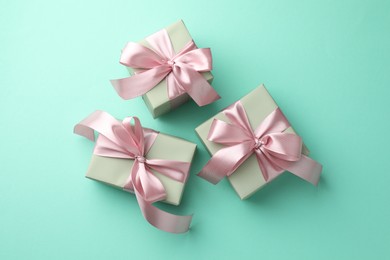 Photo of Gift boxes with bows on turquoise background, flat lay