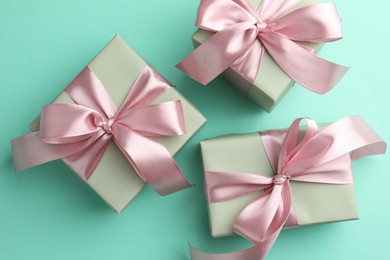 Photo of Gift boxes with bows on turquoise background, flat lay