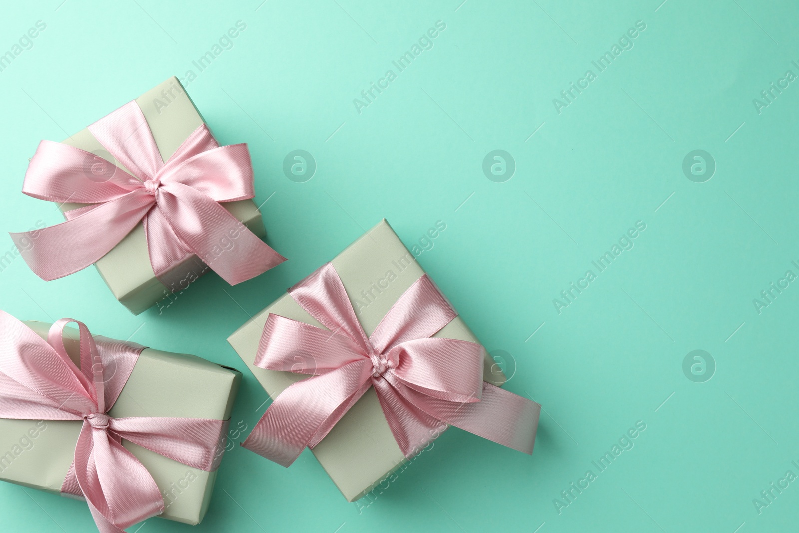 Photo of Gift boxes with bows on turquoise background, flat lay. Space for text