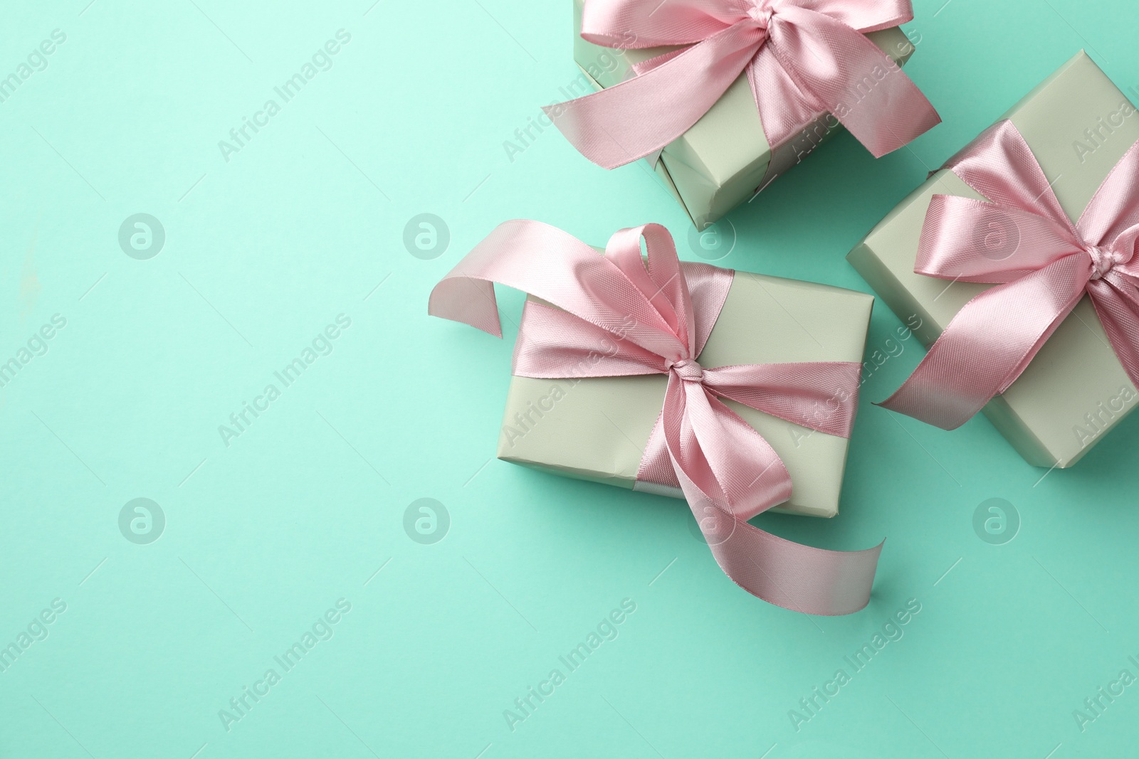 Photo of Gift boxes with bows on turquoise background, flat lay. Space for text