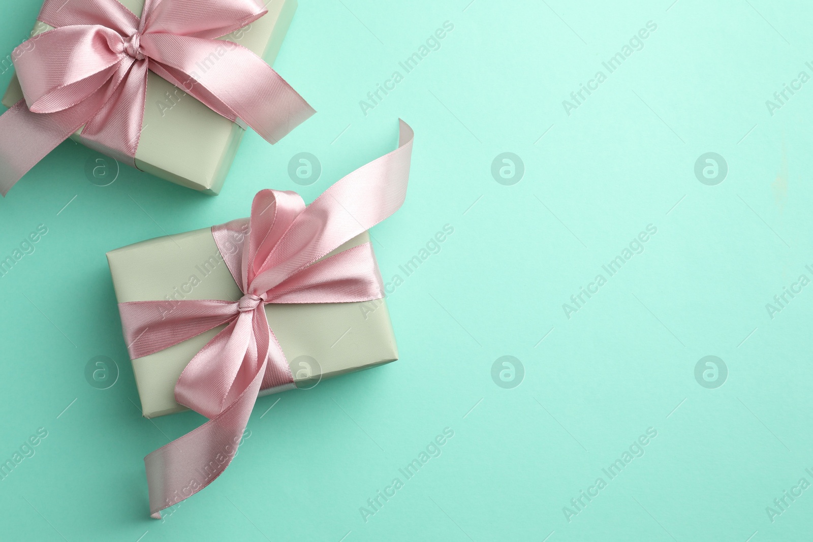 Photo of Gift boxes with bows on turquoise background, flat lay. Space for text