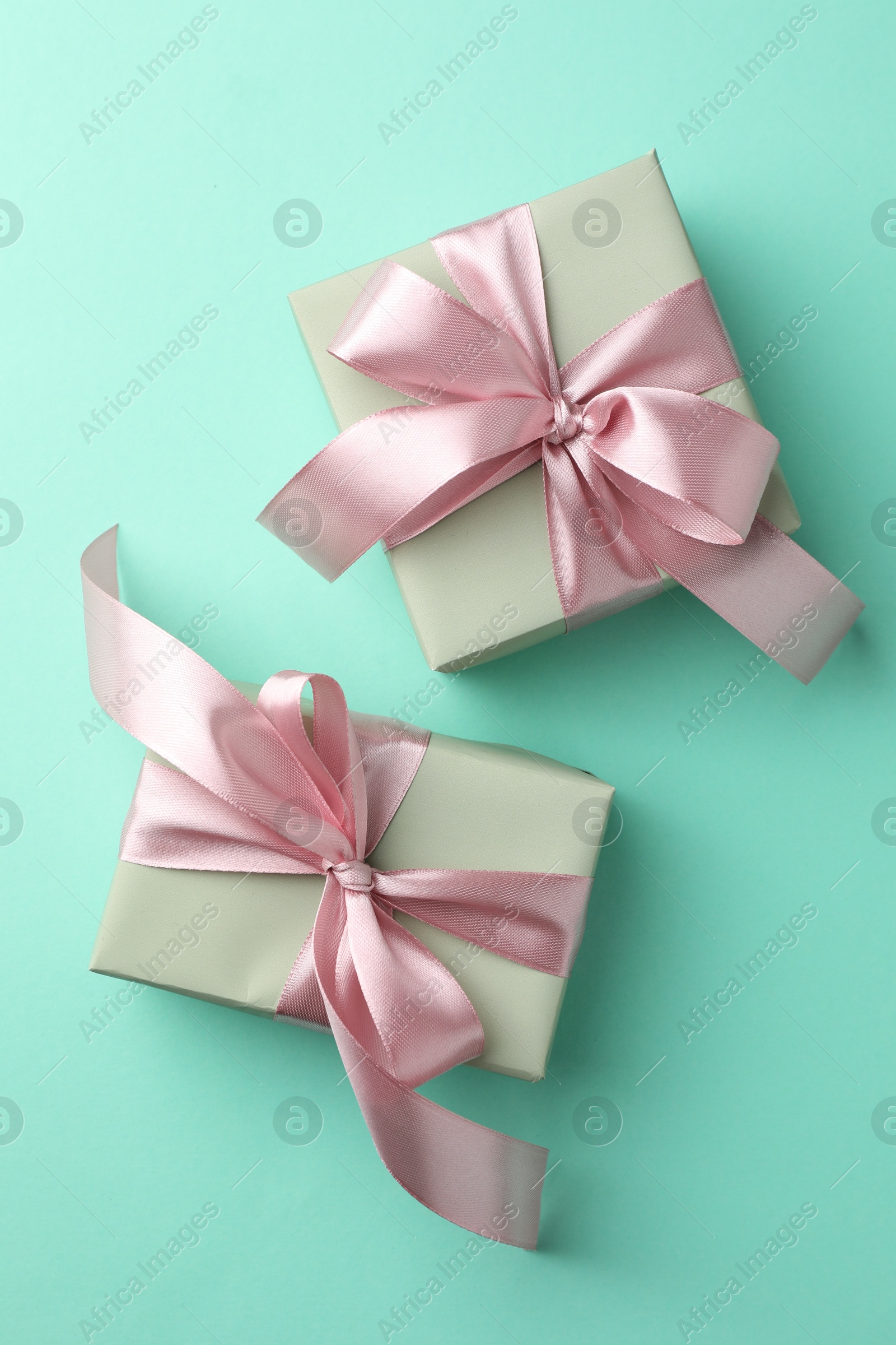 Photo of Gift boxes with bows on turquoise background, flat lay