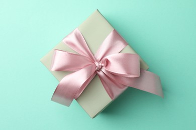 Photo of Gift box with bow on turquoise background, top view