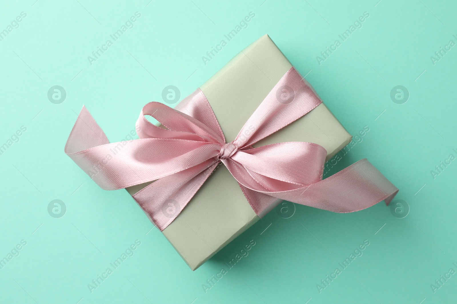 Photo of Gift box with bow on turquoise background, top view