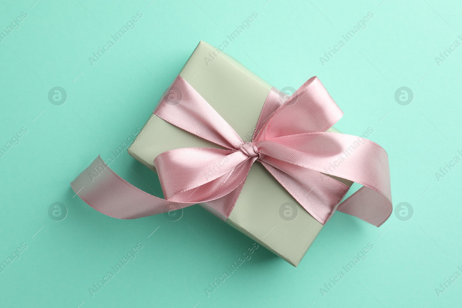 Photo of Gift box with bow on turquoise background, top view