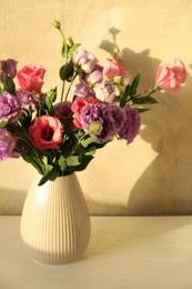 Vase with beautiful eustoma flowers on white wooden table