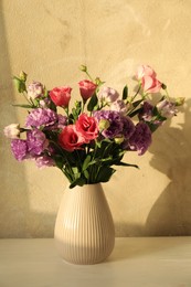 Vase with beautiful eustoma flowers on white wooden table