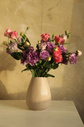 Vase with beautiful eustoma flowers on white wooden table