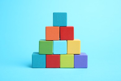 Photo of Pyramid of colorful cubes on light blue background