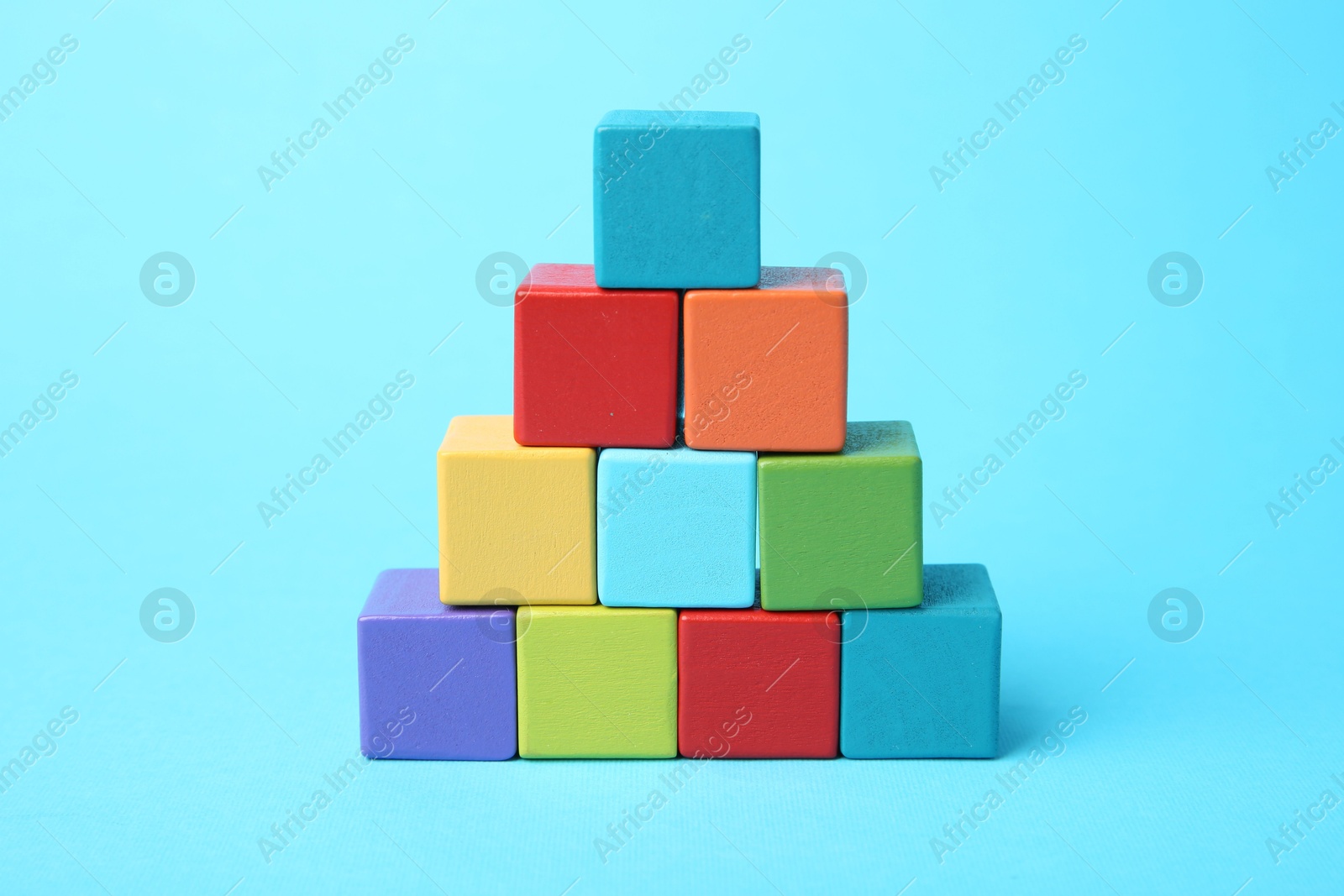 Photo of Pyramid of colorful cubes on light blue background