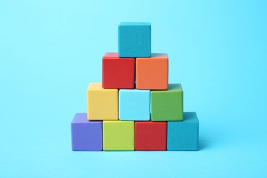 Photo of Pyramid of colorful cubes on light blue background