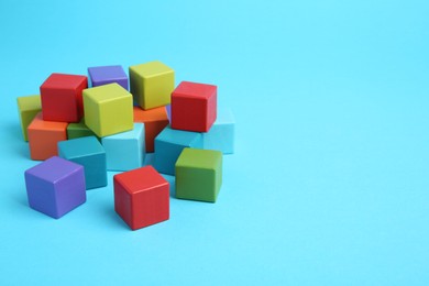 Photo of Many colorful cubes on light blue background. Space for text