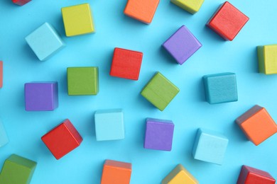 Photo of Many colorful cubes on light blue background, flat lay