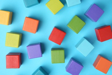 Photo of Many colorful cubes on light blue background, flat lay