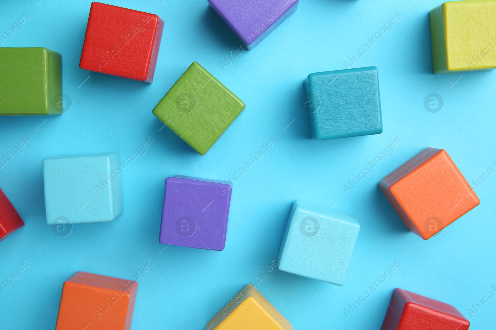 Photo of Many colorful cubes on light blue background, flat lay