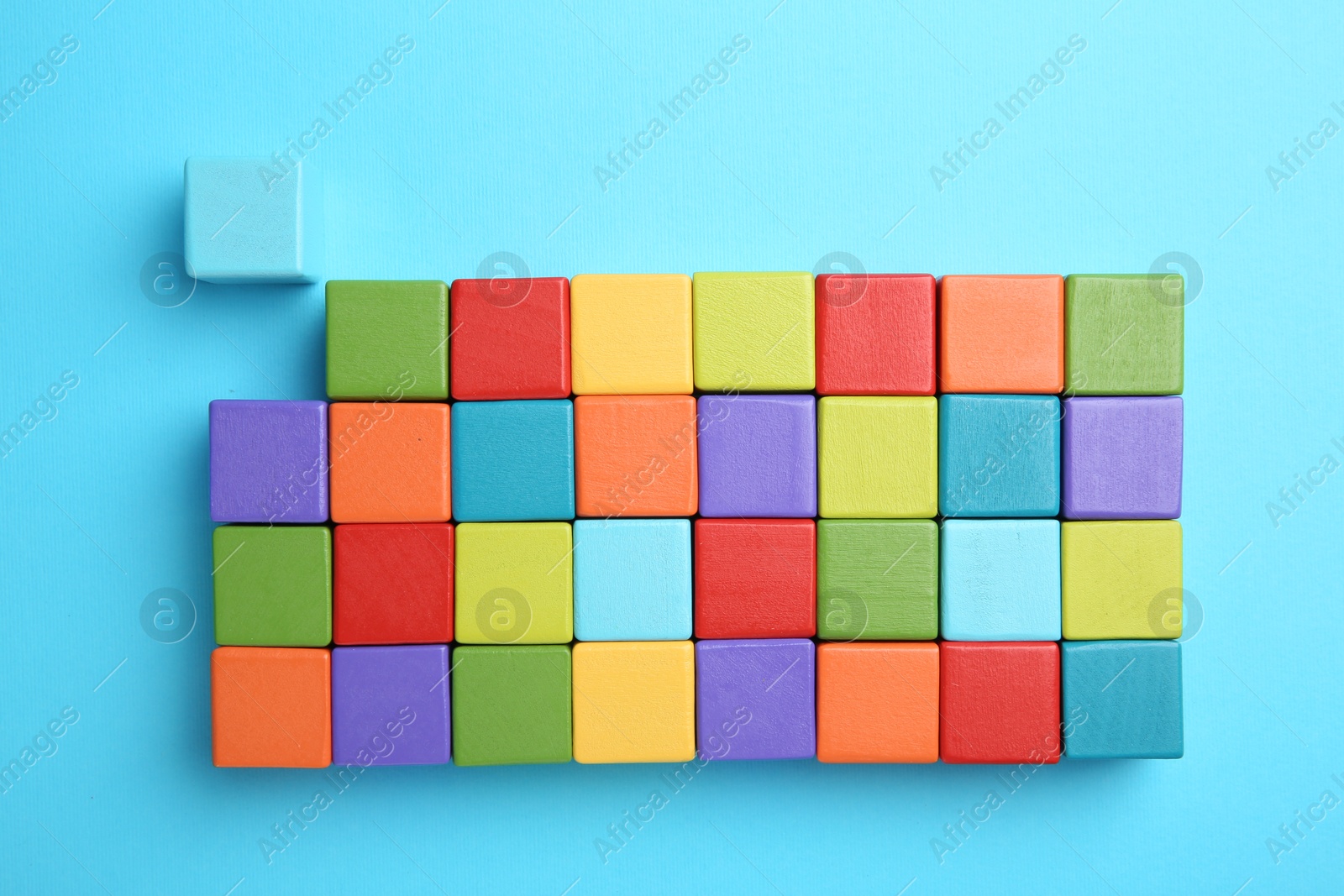 Photo of Many colorful cubes on light blue background, top view