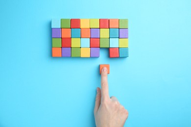 Photo of Woman with colorful cubes on light blue background, top view