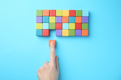 Photo of Woman with colorful cubes on light blue background, top view