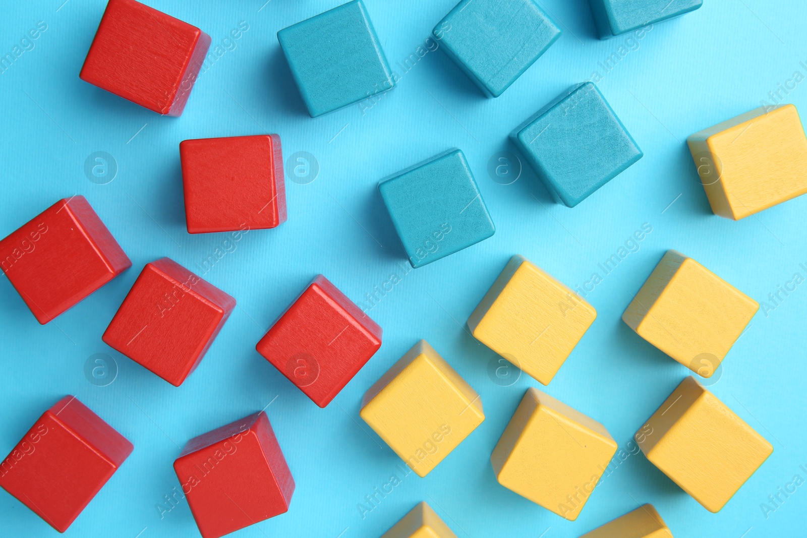 Photo of Many colorful cubes on light blue background, flat lay