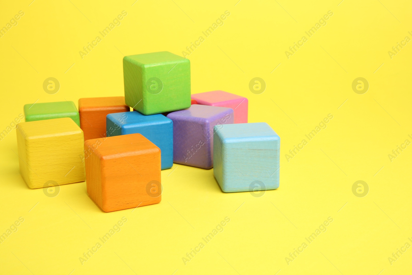 Photo of Many wooden colorful cubes on yellow background