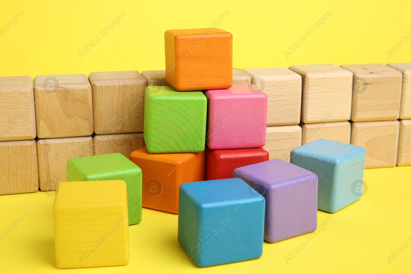 Photo of Many wooden colorful cubes on yellow background