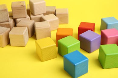 Photo of Many wooden colorful cubes on yellow background