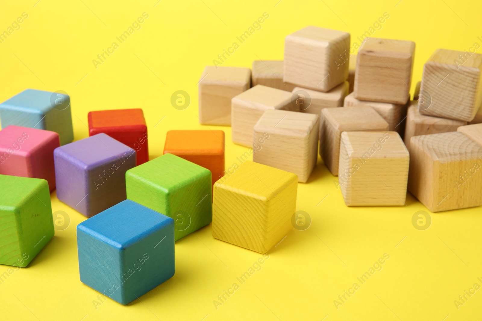 Photo of Many wooden colorful cubes on yellow background