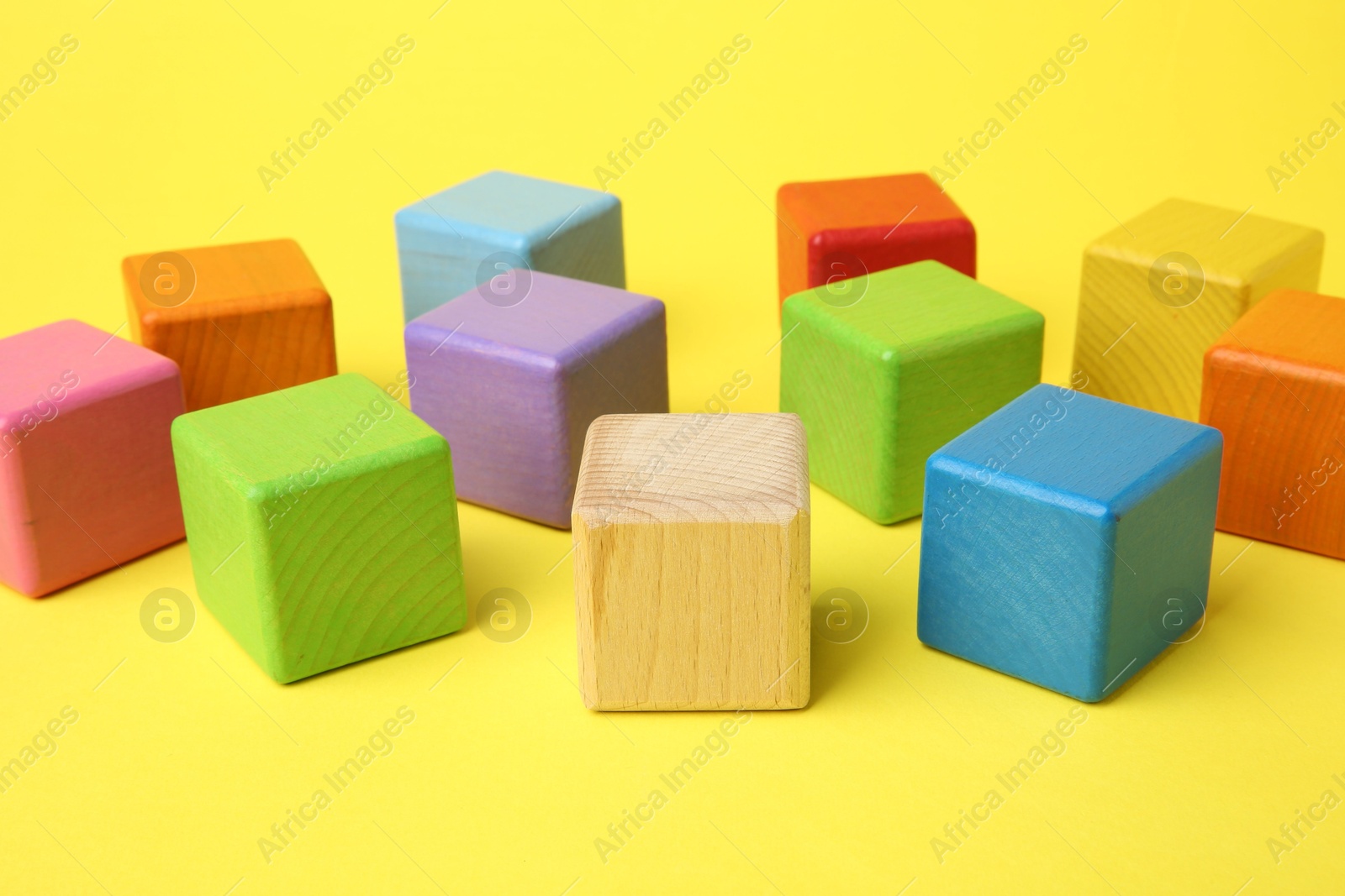 Photo of Many wooden colorful cubes on yellow background