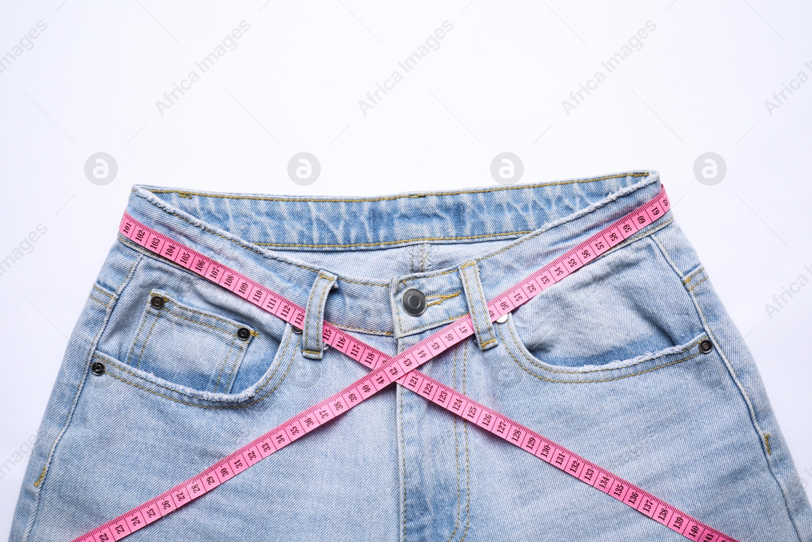 Photo of Jeans and measuring tape on white background, top view