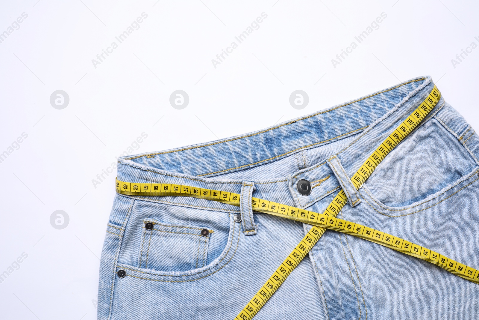 Photo of Jeans and measuring tape on white background, top view