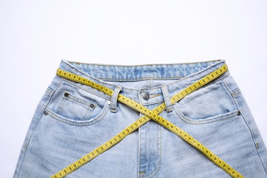 Photo of Jeans and measuring tape on white background, top view