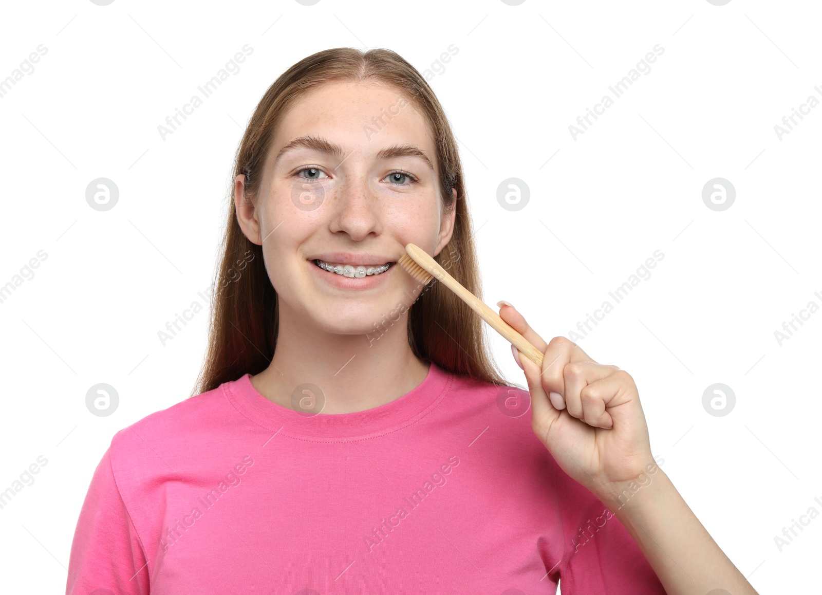 Photo of Smiling girl with braces cleaning teeth on white background