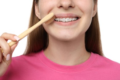 Photo of Girl with braces cleaning teeth on white background, closeup