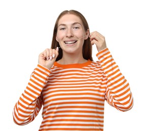 Photo of Smiling girl with braces cleaning teeth with dental floss on white background