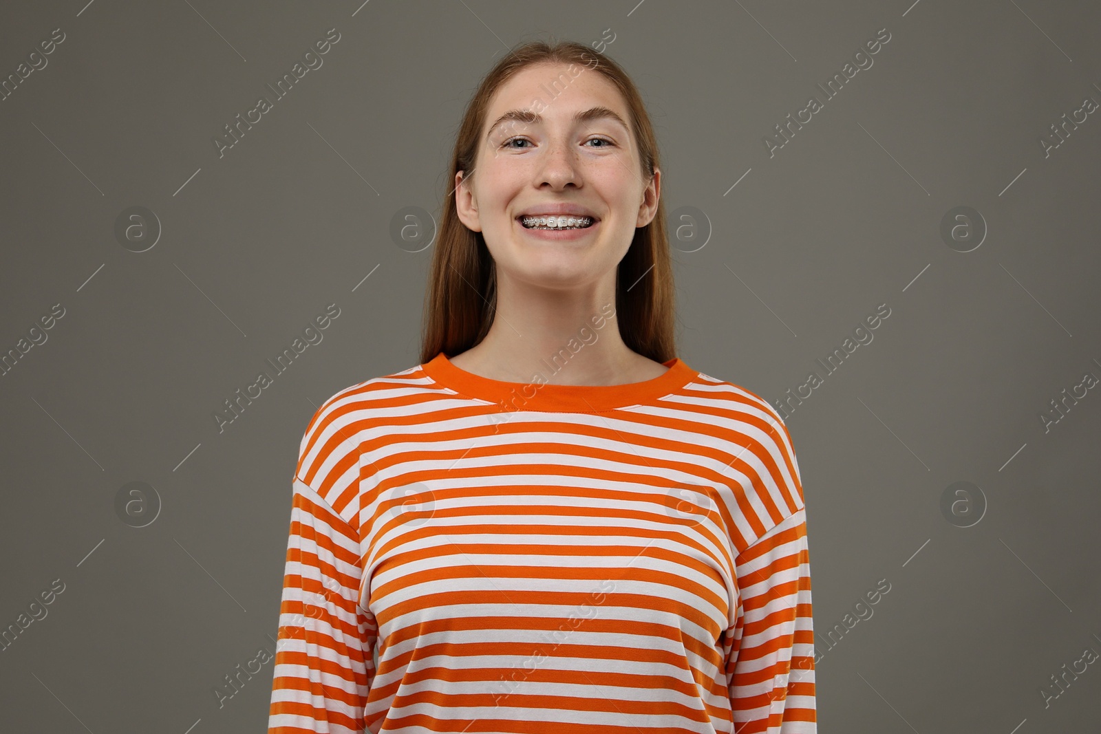 Photo of Smiling girl with braces on grey background